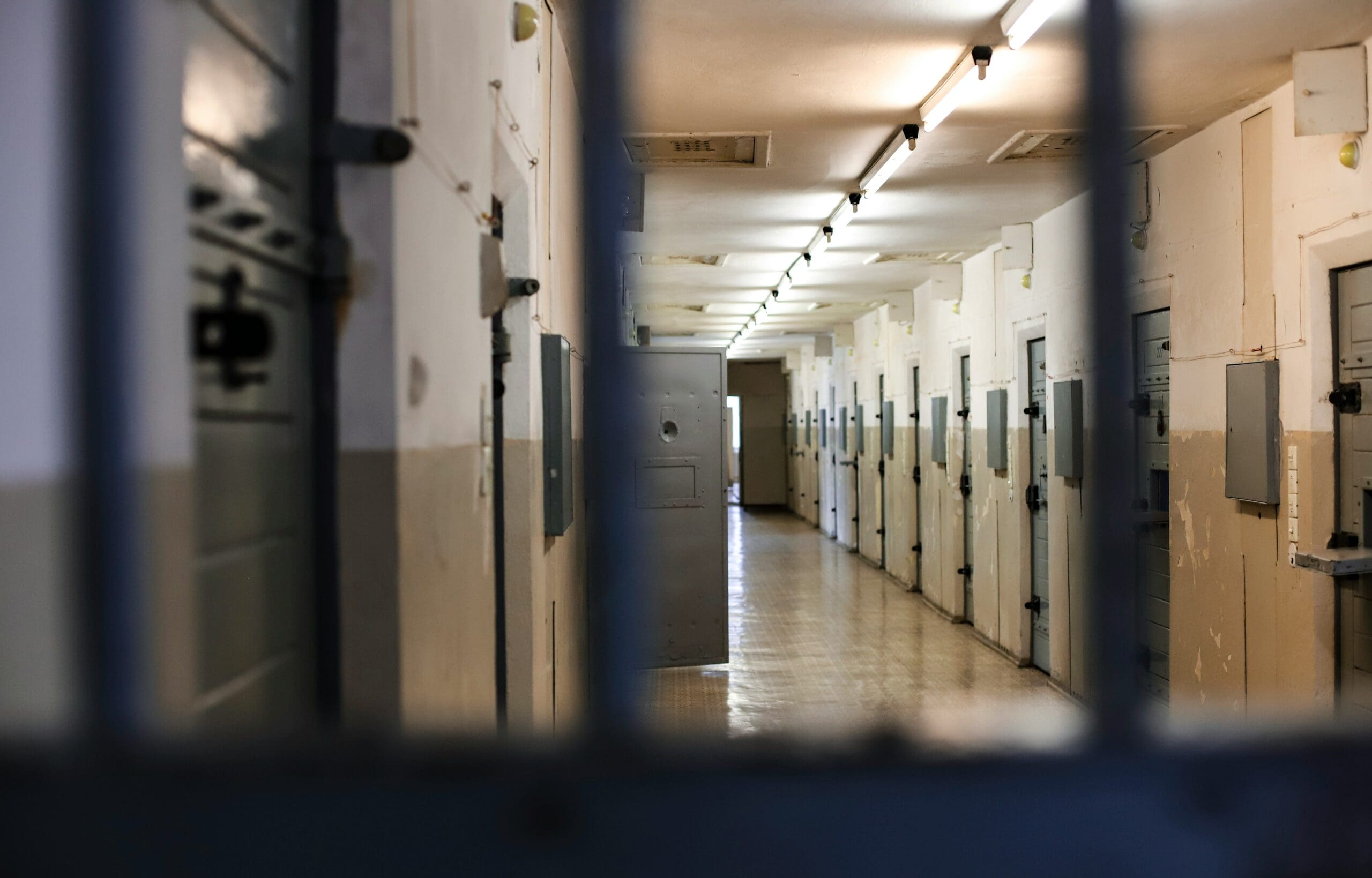 Prison corridor seen through the bars of a cell door